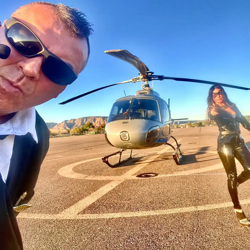 Man and woman with helicopter on tarmac, sunny day, outdoor scene.